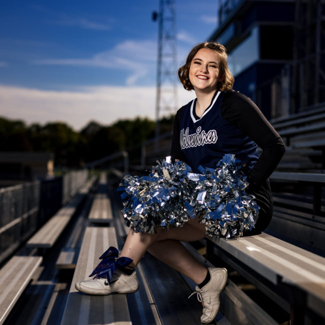 High School Senior Portrait of a cheerleader sitting in the stands