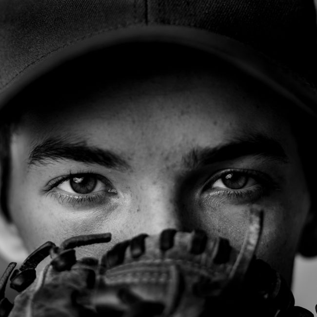 Senior portrait of student of baseball player with his glove in front of his face