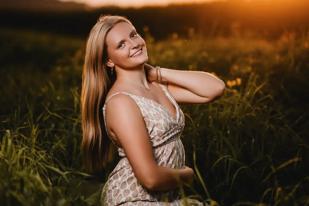 Female high school senior posing outdoors at sunset during golden hour in Owatonna, Minnesota, during a senior portrait session.